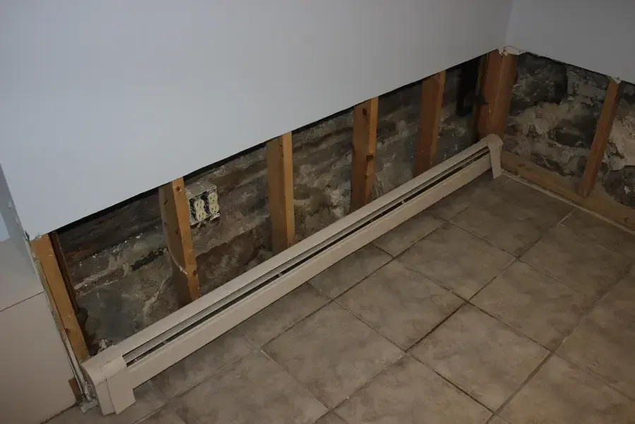 A wall opened above a baseboard heater so the cavity can dry