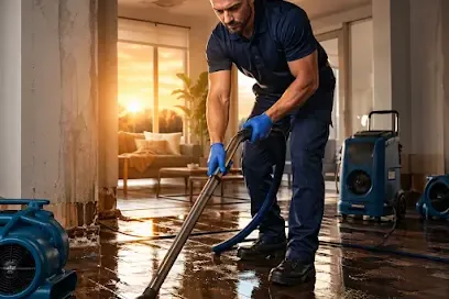 A restoration technician extracting standing water from the floor of a home