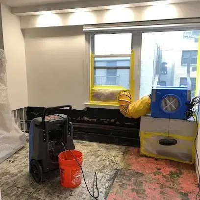 Chaska structural drying: a dehumidifier and air mover in a room with flooring removed